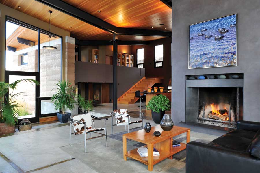 The home's Rumford-style firebox was designed by Count Rumford, a contemporary of Benjamin Franklin. Its shallow design increases its heat output and efficiency. Above it, a recessed mantel displays the couple's collection of Japanese teapots. The duck painting by Ewoud De Groot, cowhide chairs and Santa Clara pottery from the Tewa Tribe lend a regional feel to the sitting area.